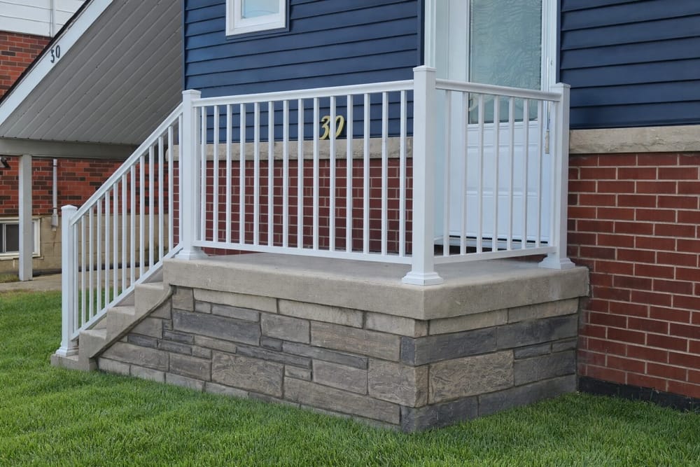 Stone porch with white railing and brick exterior