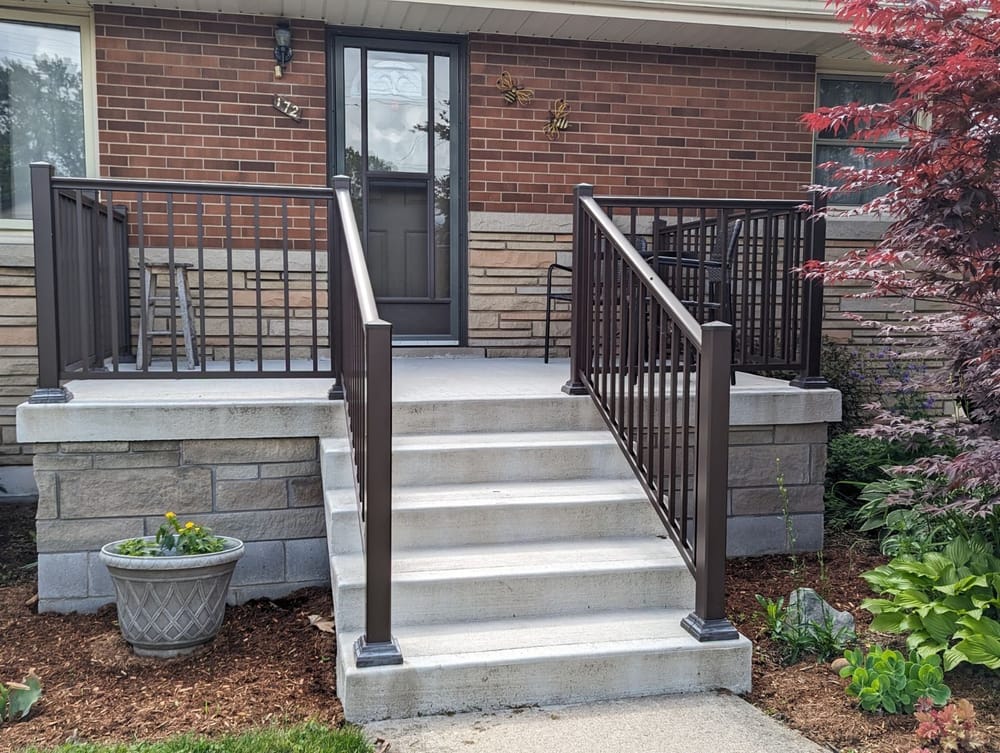 Concrete porch with dark metal railing and stone