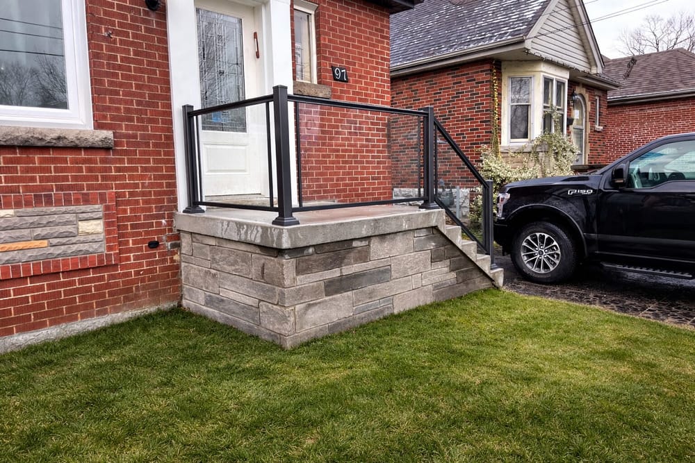 Stone porch with black glass panel railing