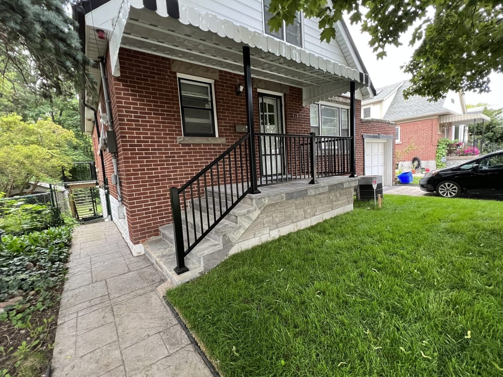 Covered porch with stone facade and black railing