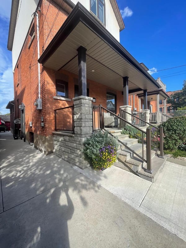 Stone column porch with bronze railing and flagstone steps