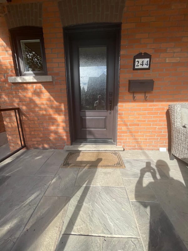 Dark entry door with flagstone porch floor