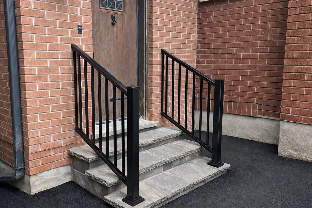Black aluminum railing on stone steps with brick exterior